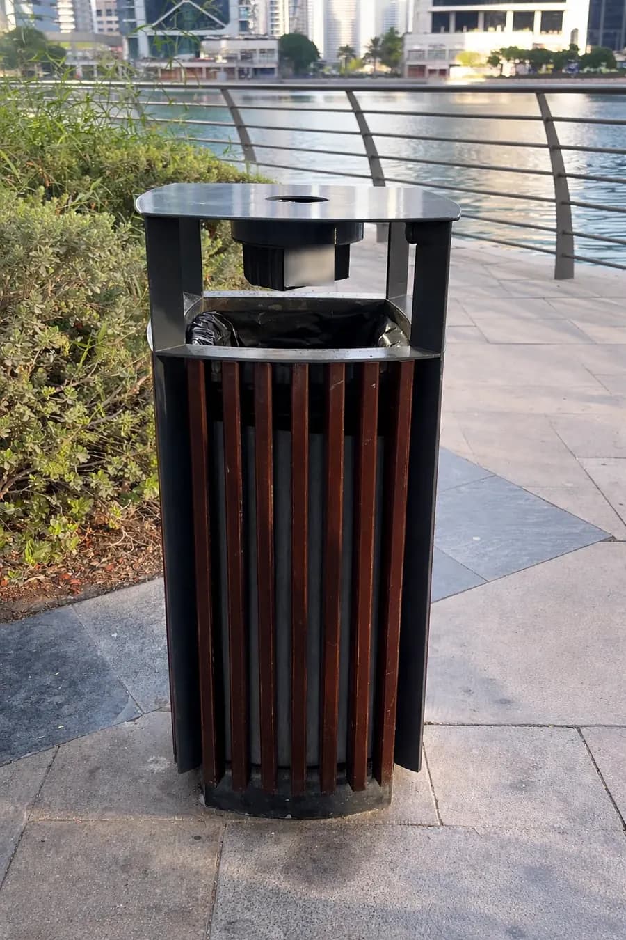 Street litter bin on a waterfront promenade fitted with a BrighterBins fill-level sensor under the lid